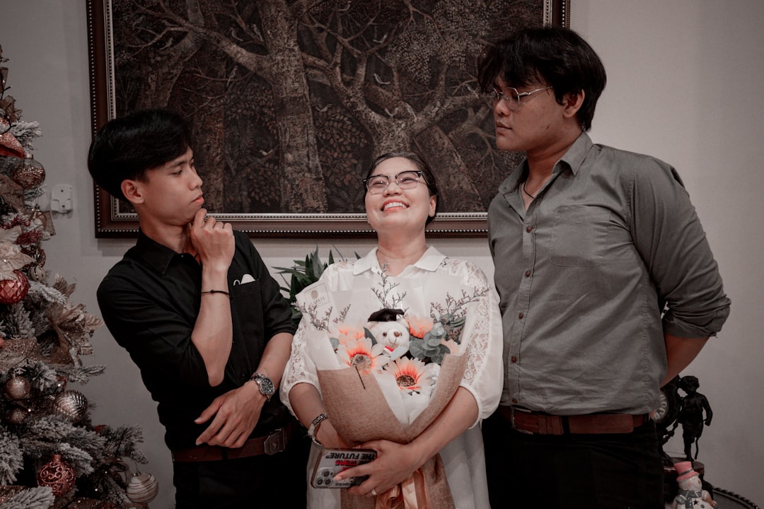 three people standing in front of a christmas tree