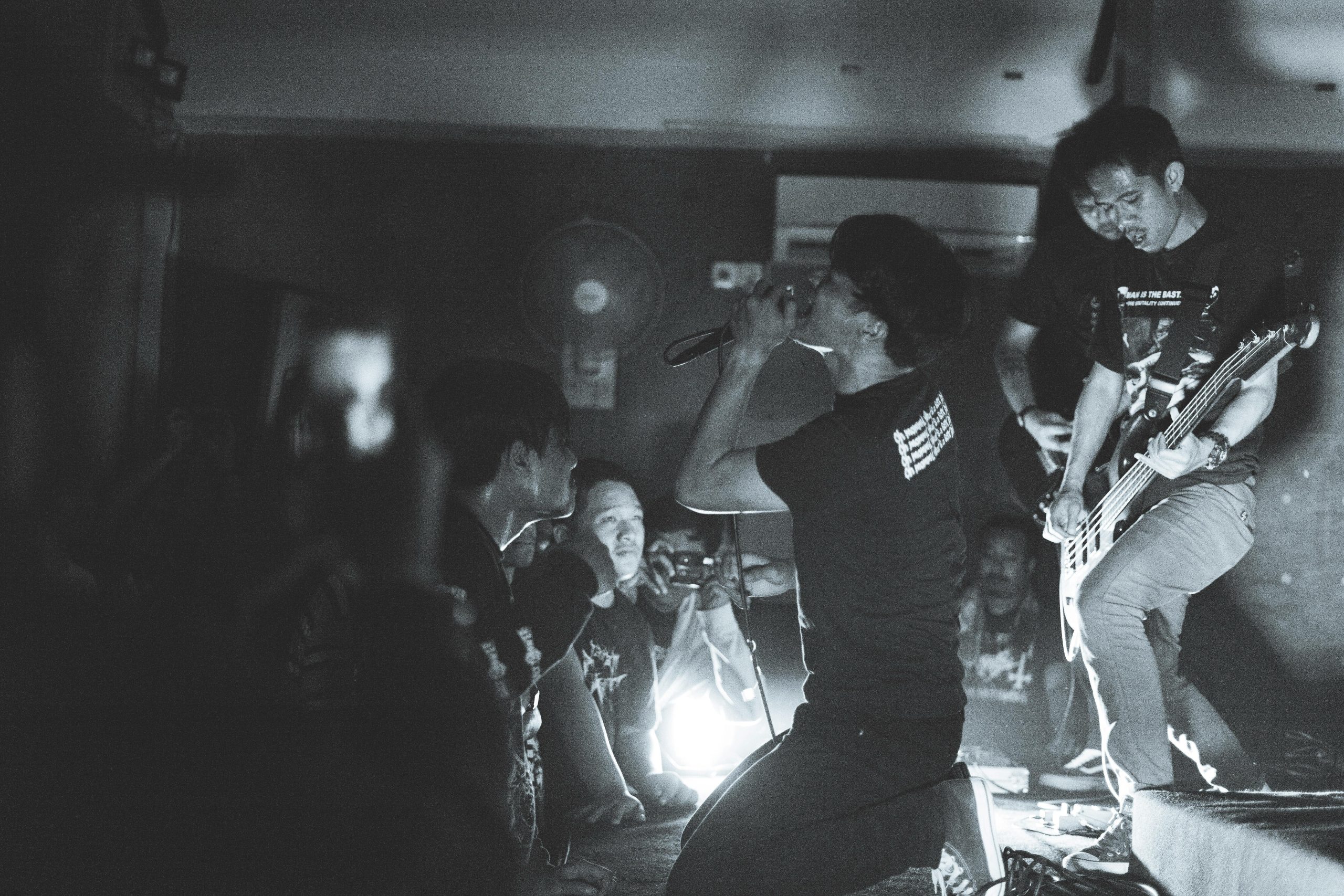 Black and white photo of a live rock performance with a singer and guitarist captivating an audience.