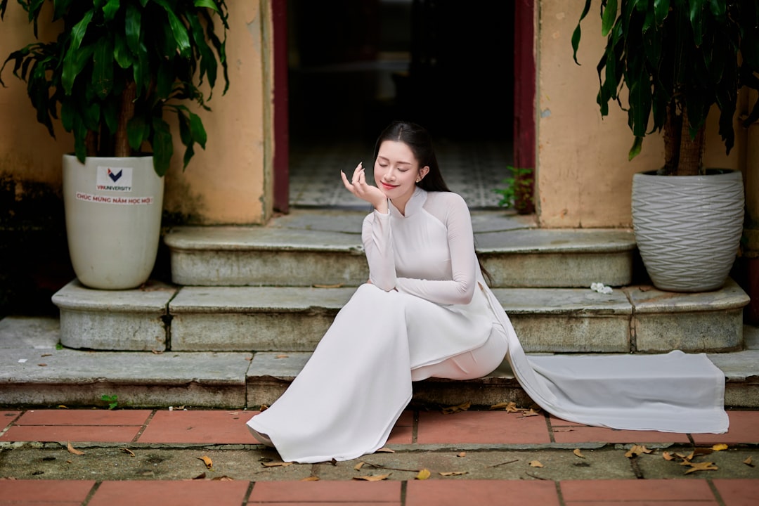 A woman in a white dress sits on steps.